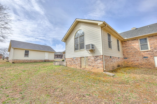 view of side of home featuring brick siding, a wall mounted air conditioner, and a yard