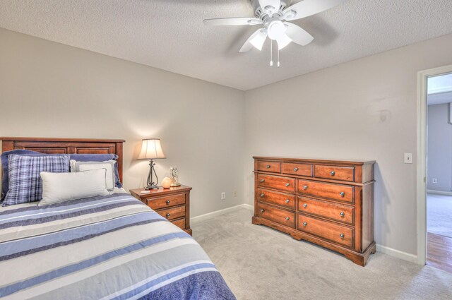 bedroom with baseboards, light colored carpet, ceiling fan, and a textured ceiling