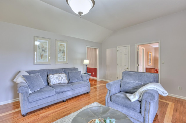 living area with baseboards, lofted ceiling, and wood finished floors