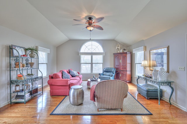 living room with baseboards, ceiling fan, vaulted ceiling, and light wood finished floors