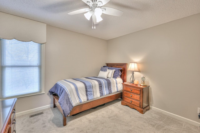 carpeted bedroom with a ceiling fan, baseboards, visible vents, and a textured ceiling