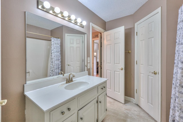 full bathroom featuring a shower with shower curtain, a textured ceiling, vanity, and baseboards