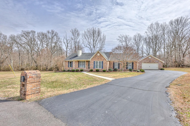 view of front of house with driveway, a front lawn, an attached garage, brick siding, and a chimney