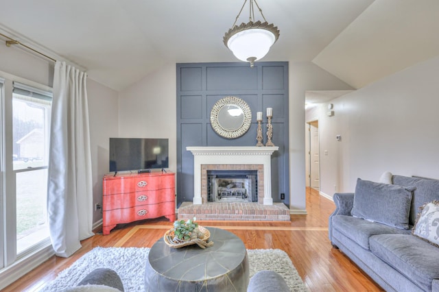 living room featuring lofted ceiling, wood finished floors, and a fireplace