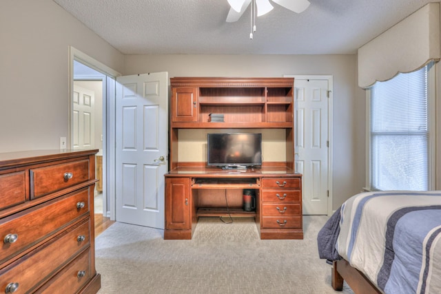 bedroom featuring light colored carpet, ceiling fan, and a textured ceiling