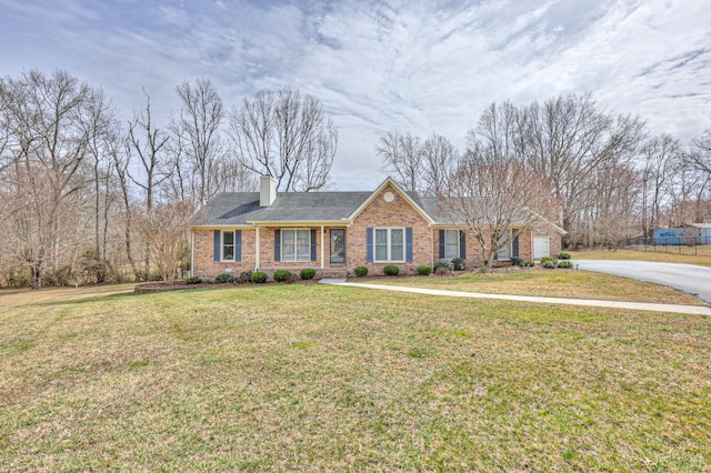 ranch-style home with a front lawn, brick siding, driveway, and a chimney