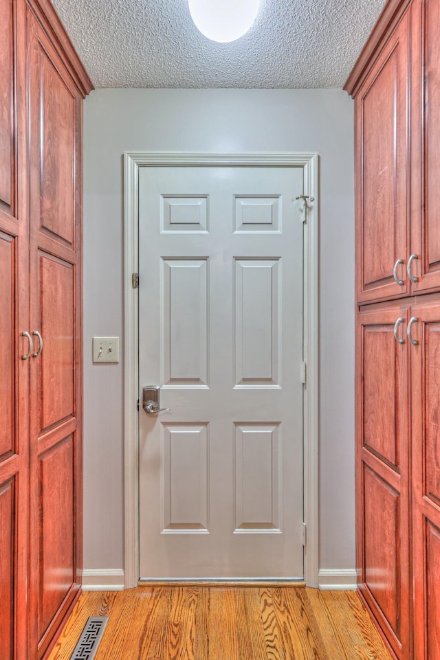 interior space with baseboards, wood finished floors, visible vents, and a textured ceiling