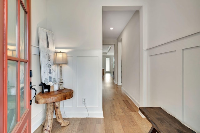 hall with a decorative wall and light wood-style flooring