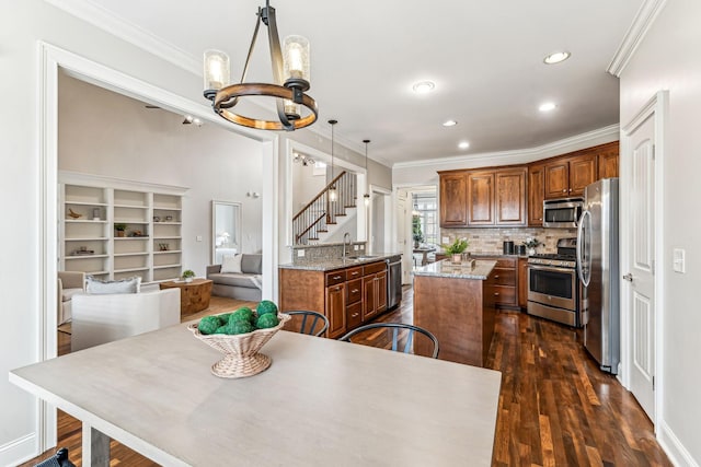 kitchen with a kitchen island, crown molding, a notable chandelier, stainless steel appliances, and a sink