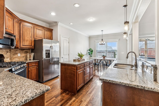 kitchen featuring a center island, light stone countertops, decorative backsplash, appliances with stainless steel finishes, and a sink