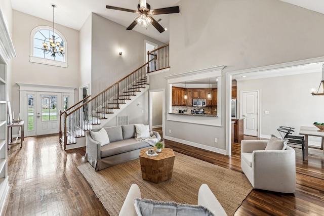 living area with visible vents, baseboards, stairway, ceiling fan with notable chandelier, and dark wood-style flooring