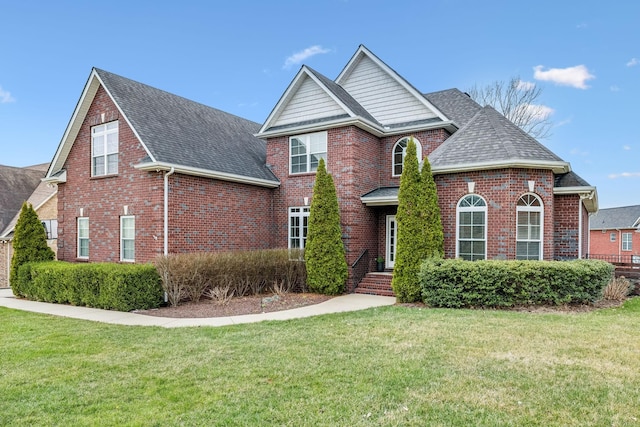 traditional-style house with brick siding, roof with shingles, and a front yard