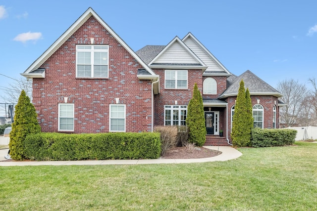 traditional-style home featuring brick siding, a shingled roof, a front lawn, and fence