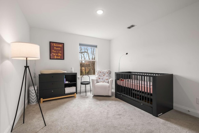 bedroom with visible vents, a nursery area, baseboards, and carpet