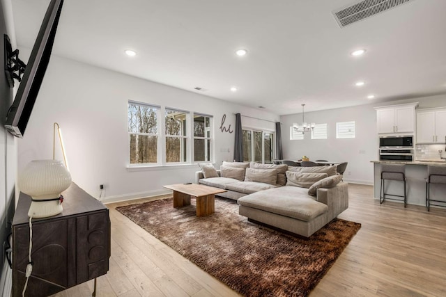 living area featuring visible vents, baseboards, recessed lighting, light wood-style floors, and a notable chandelier