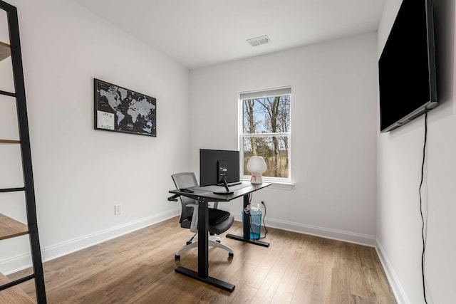 office space with wood finished floors, visible vents, and baseboards