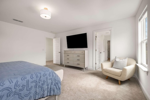 bedroom featuring visible vents, light carpet, and baseboards