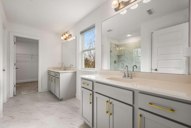 bathroom featuring visible vents, two vanities, a stall shower, marble finish floor, and a sink