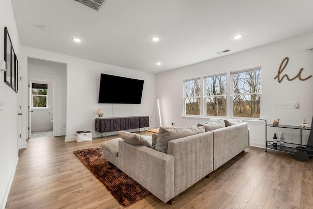 living room with recessed lighting, visible vents, and wood finished floors