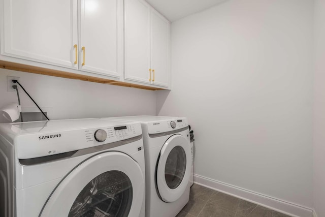 laundry room featuring baseboards, cabinet space, separate washer and dryer, and dark tile patterned floors