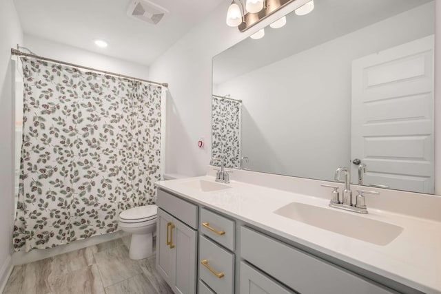 bathroom with double vanity, toilet, visible vents, and a sink