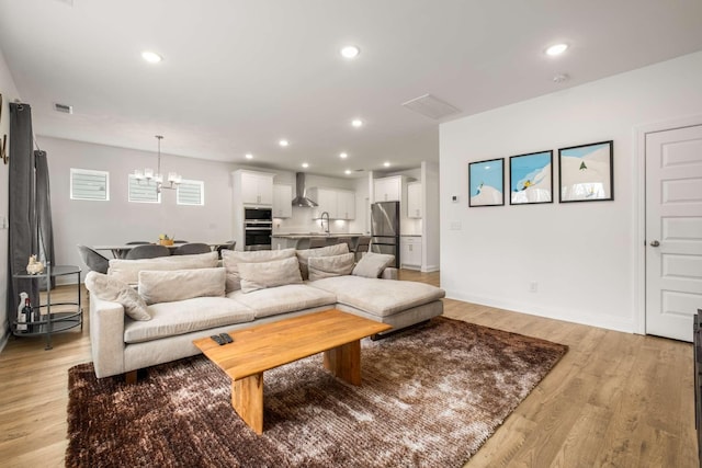 living area featuring light wood-style flooring, a notable chandelier, recessed lighting, and visible vents