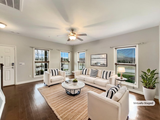 living area featuring visible vents, a ceiling fan, baseboards, and dark wood-style flooring