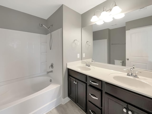 full bath featuring double vanity, toilet, bathtub / shower combination, and a sink