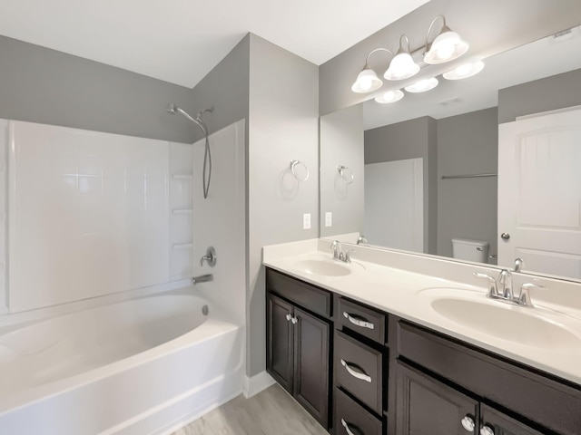 bathroom featuring double vanity, toilet, tub / shower combination, and a sink