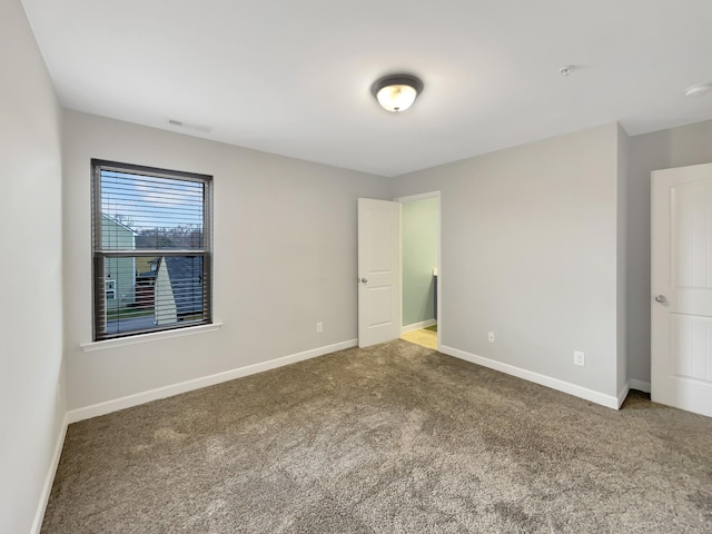 carpeted spare room with visible vents and baseboards