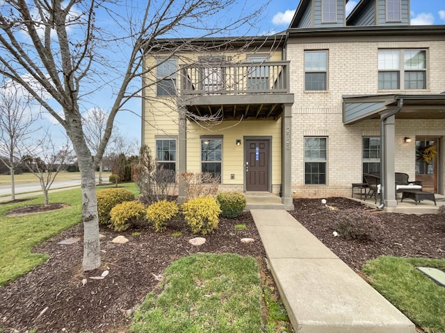 townhome / multi-family property featuring a patio, brick siding, and a balcony