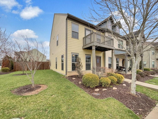 view of front facade with brick siding, fence, a front yard, a balcony, and a patio