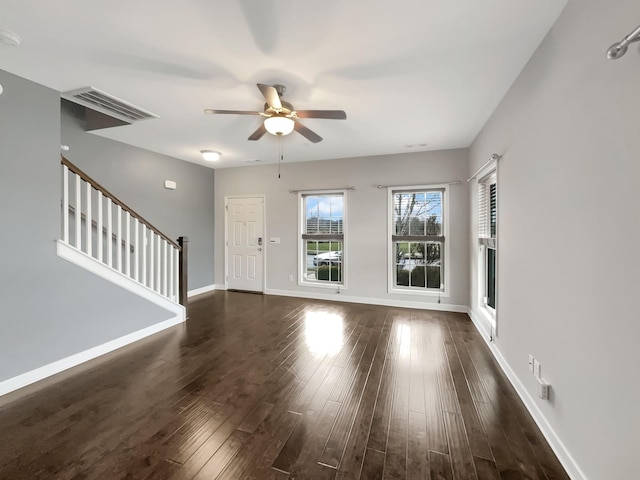 unfurnished living room featuring dark wood-style floors, visible vents, baseboards, ceiling fan, and stairs