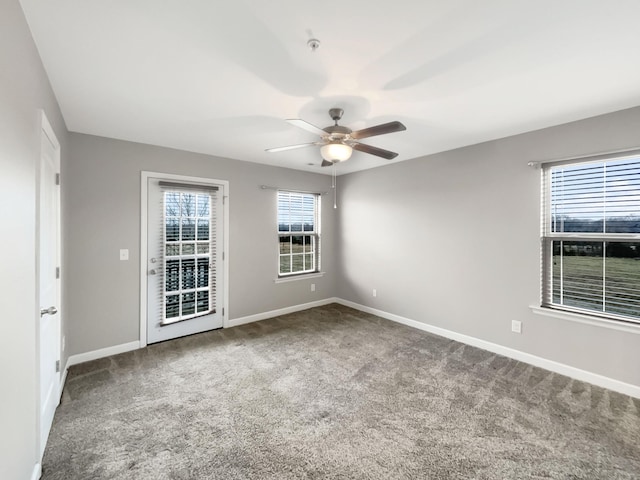 carpeted empty room with a ceiling fan and baseboards