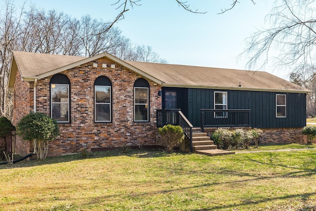 view of front of property featuring board and batten siding, a front lawn, brick siding, and a shingled roof