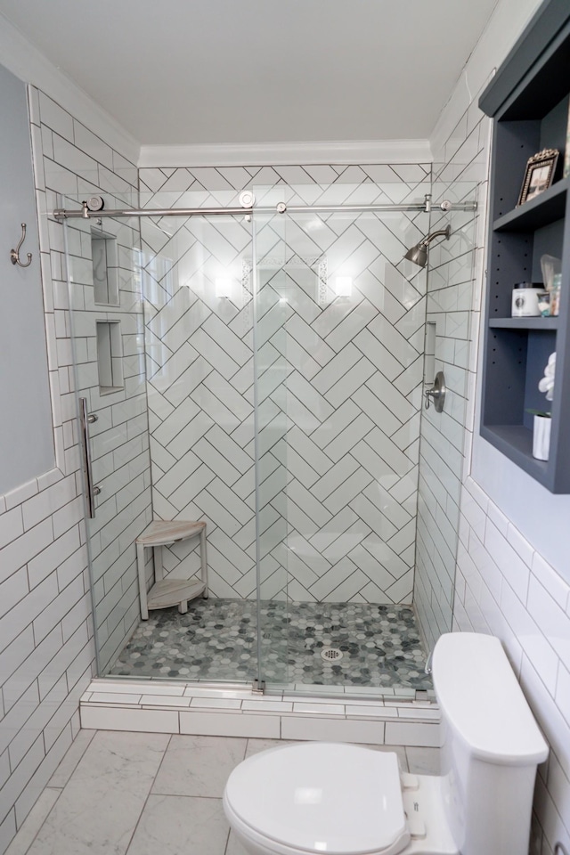 bathroom with marble finish floor, toilet, tile walls, and a shower stall