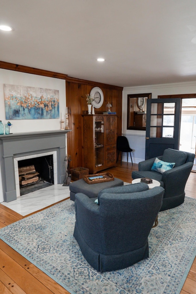 living room featuring wood finished floors, crown molding, recessed lighting, and a fireplace