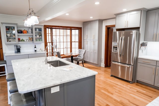 kitchen featuring ornamental molding, stainless steel fridge with ice dispenser, gray cabinets, and a sink