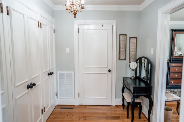 entrance foyer featuring light wood-type flooring, visible vents, an inviting chandelier, and crown molding