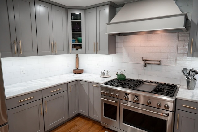 kitchen with double oven range, gray cabinetry, and custom range hood