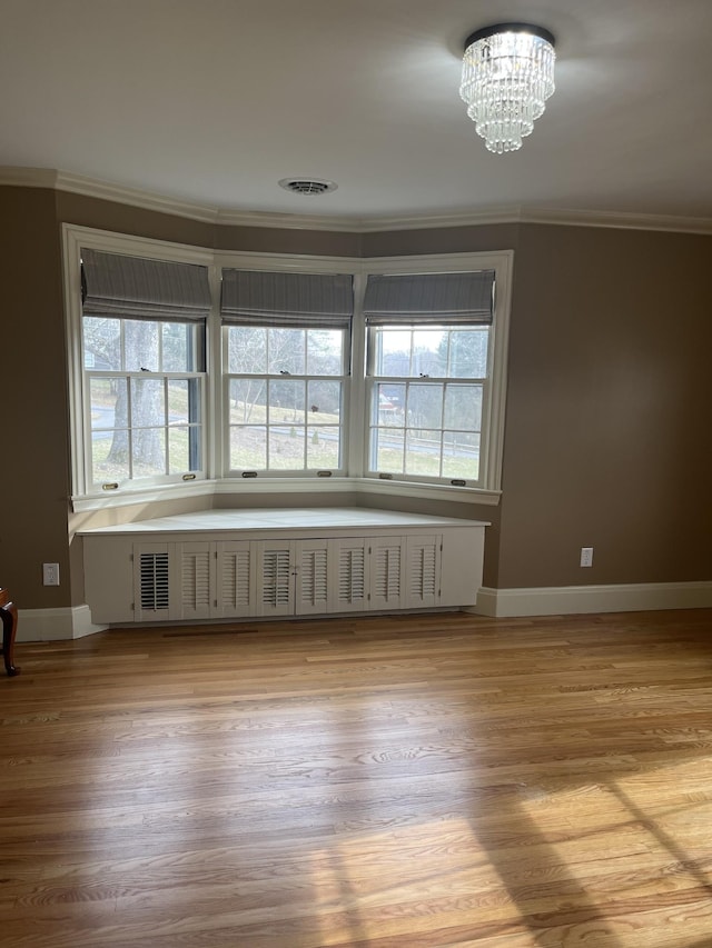 unfurnished room with visible vents, radiator, ornamental molding, wood finished floors, and a notable chandelier