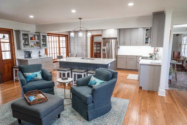 living area featuring recessed lighting, light wood-style floors, and crown molding