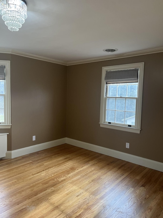 unfurnished room featuring visible vents, baseboards, a chandelier, light wood-type flooring, and ornamental molding