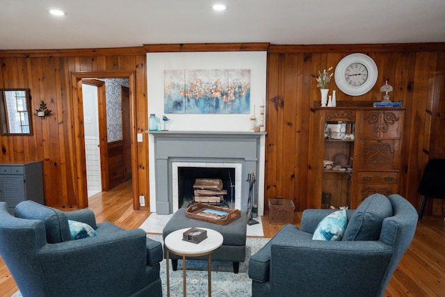 living room featuring a fireplace with flush hearth, wood finished floors, and wood walls