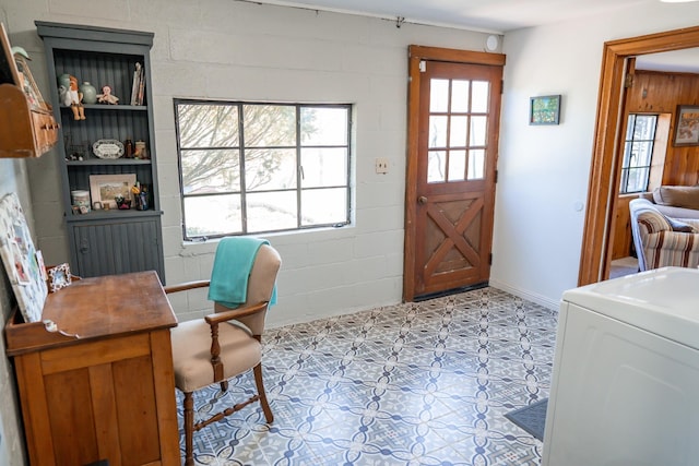 office space with tile patterned floors, washer / dryer, and concrete block wall