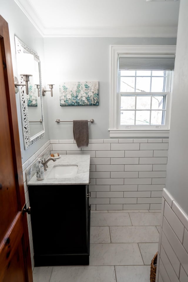 bathroom featuring wainscoting, tile walls, and ornamental molding