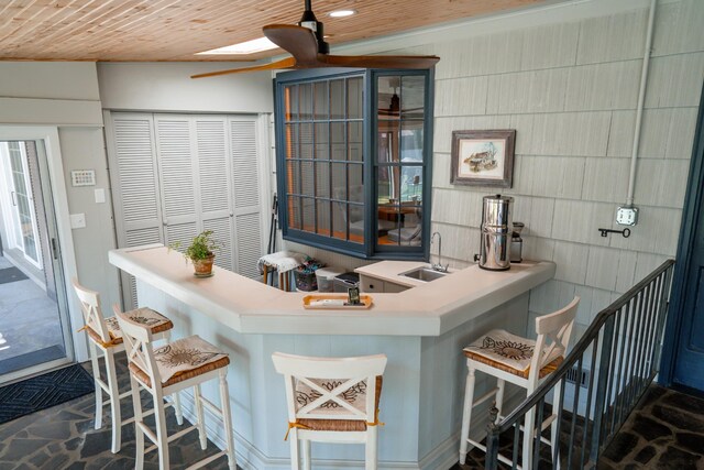 bar with a sink, a skylight, and wooden ceiling