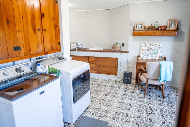 laundry room with concrete block wall, separate washer and dryer, light floors, and laundry area