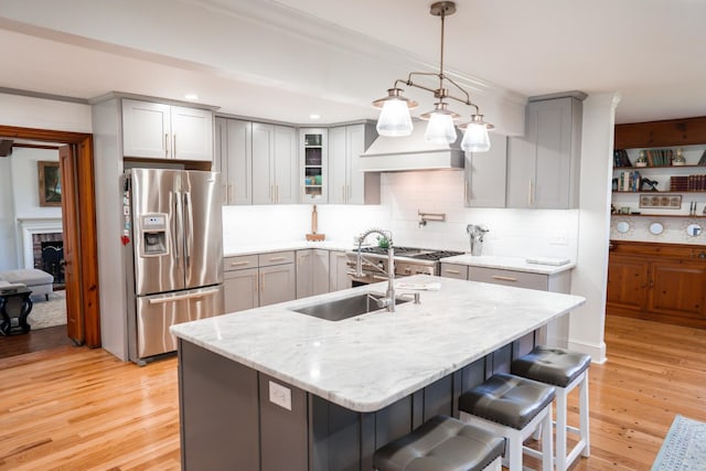 kitchen with light stone counters, light wood-style floors, stainless steel fridge, and gray cabinetry