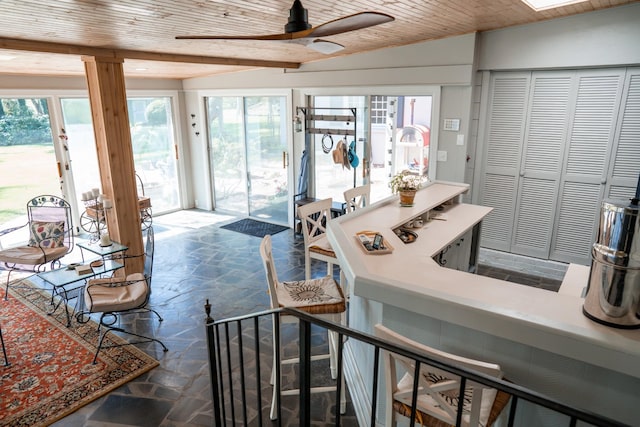 kitchen featuring ceiling fan, vaulted ceiling, wood ceiling, and stone finish flooring